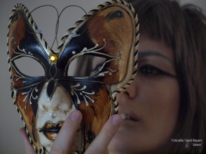 Hedy Kramer mirando una máscara veneciana con el movimiento de ir a ponérsela 